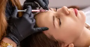injector administering a dermal fillers injection into a patient's cheek or jawline to restore facial volume and contour.